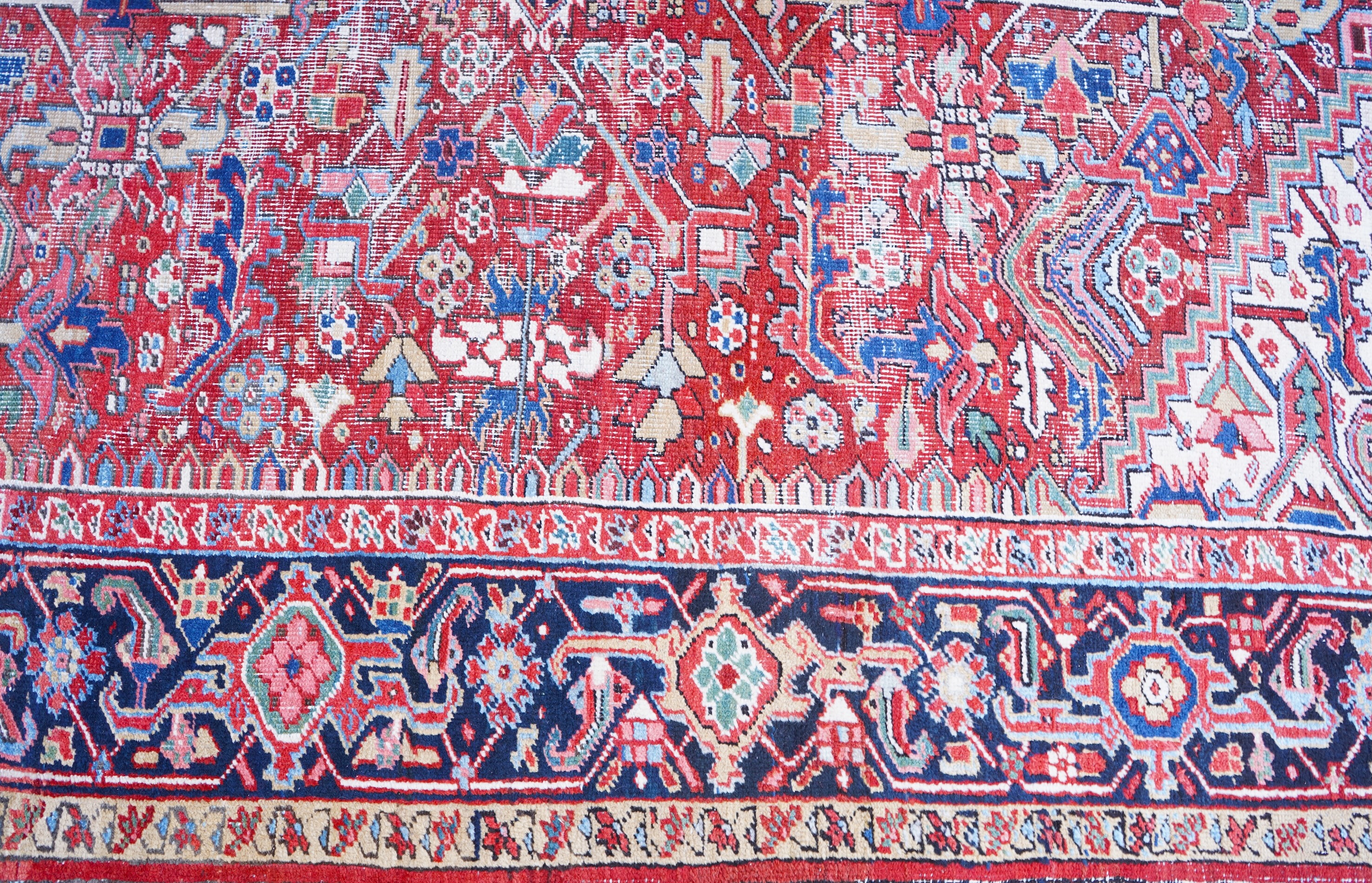 An antique Heriz brick red ground carpet with central